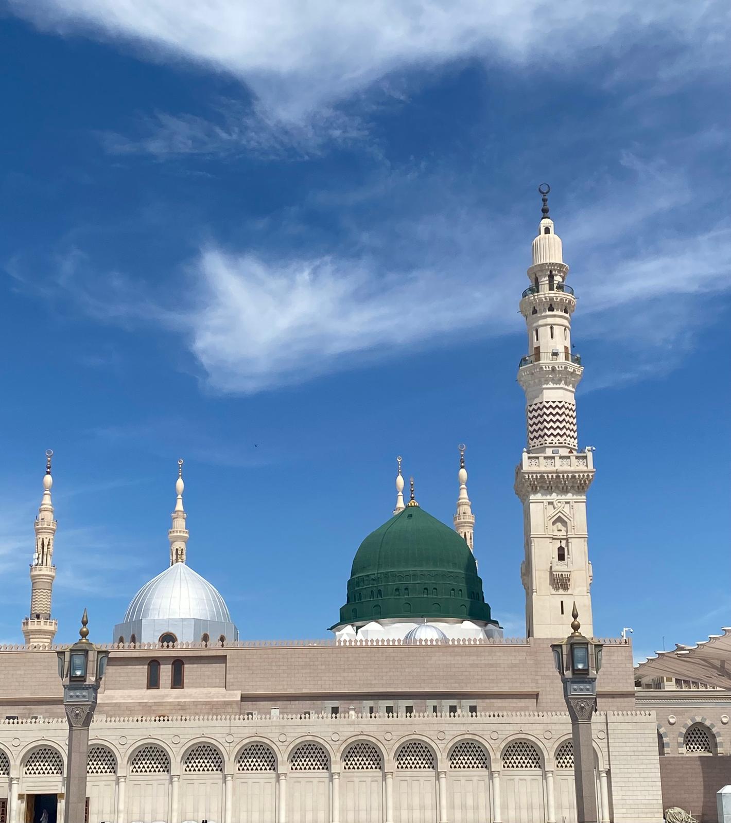 The green dome of Masjid an-Nabawi in Madina under a blue sky